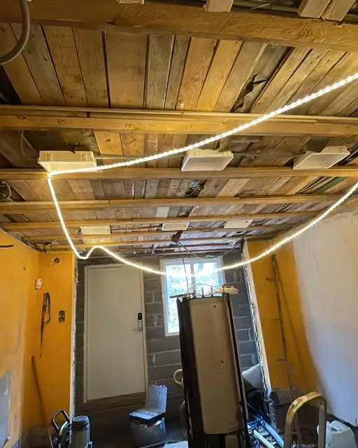 Rum under renovering med öppet trätak, armaturer och en tänd LED-slinga