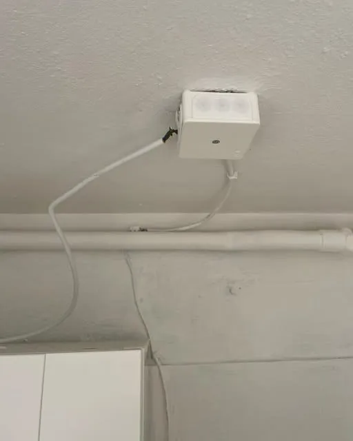 Vit kopplingsdosa i taket med kabel dragen längs väggen